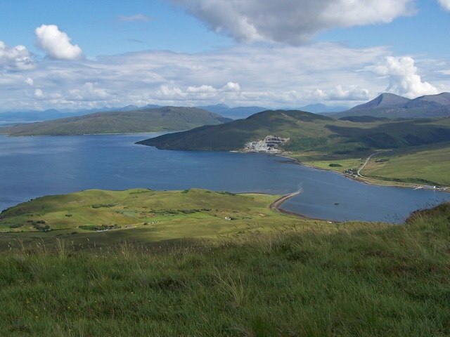 Rubh' an Tòrra Mhòir from Ben Lee This view is from the steep and grassy eastern slope of Ben Lee over the mouth of Loch Sligachan. The loch extends to the right. Sunlight is catching Tòrr Mhòr and Tòrr Beag, two hills on the grazing land to the east of Peinachorrain. The land ends at the point called Rubh' an Tòrra Mhòir. The road on the right is the A87 Sligachan to Broadford road. The stone quarry at Sconser in the side of Meall Buidhe is clearly visible. The pyramid-shaped mountain in the background is Beinn na Caillich.