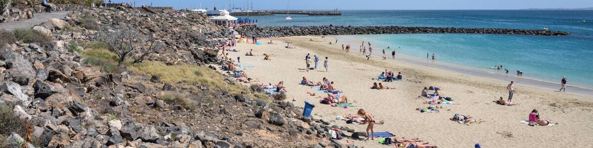 Photo "Lanzarote, Playablanca: the beach towards the marina. The isle of Fuerteventura is seen in the right background." by Cayambe (Creative Commons Attribution-Share Alike 4.0) / Cropped from original