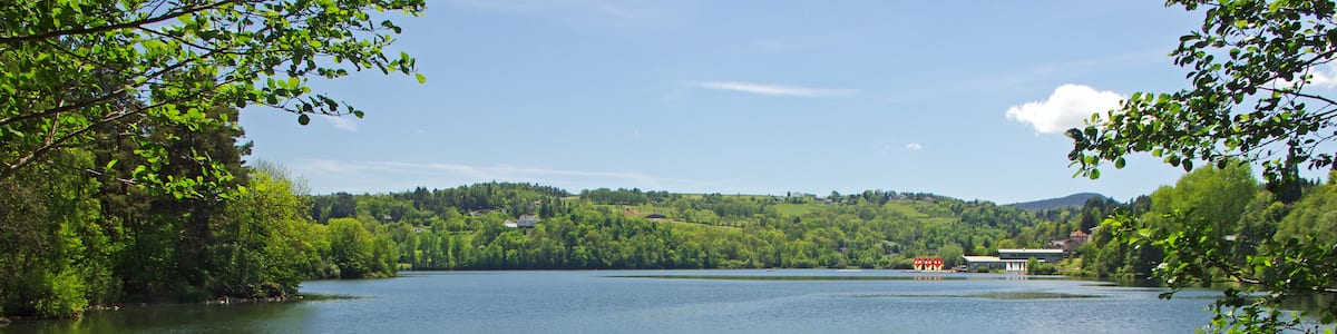 Photo "Aydat (Puy-de-Dôme) Lac d'Aydat. Le lac d'Aydat est le plus grand lac naturel d'Auvergne (65 ha). Le lac provient de la retenue de la rivière de la Veyre par une coulée de lave (La cheire* d'Aydat). La cheire d'Aydat est en réalité le résultat de deux coulées, l'une issue du Puys de la Vache et l'autre du Puys de Lassolas. La datation de fragments de bois calciné retrouvés sous la lave donne un âge d'environ 7700 ans à cette coulée commune. Cheire ou cheyre : champ de lave rugueux. Aydat (Puy-de-Dôme) Lake Aydat. Aydat Lake is the largest natural lake in Auvergne (65 ha). The lake comes from retaining the River Veyre by a lava flow (* The cheire Aydat). The cheire Aydat is actually the result of two lava flows, one end of the Puy de la Vache and the other Puys Lassolas. The dating of calcined wood fragments found under the lava gives an age of about 7700 years this common casting. Cheire or Cheyre: rough lava field." by Daniel Jolivet (Creative Commons Attribution 2.0) / Cropped from original