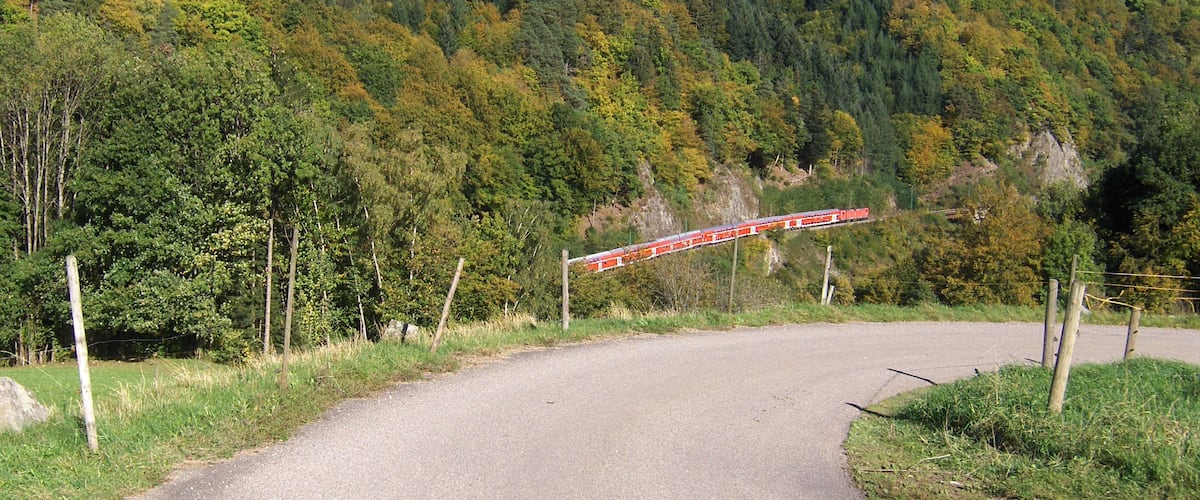 Zug von DB Regio mit 6 Doppelstockwagen und 2 Loks der Baureihe 143 auf der Fahrt ins Höllental oberhalb von Falkensteig.