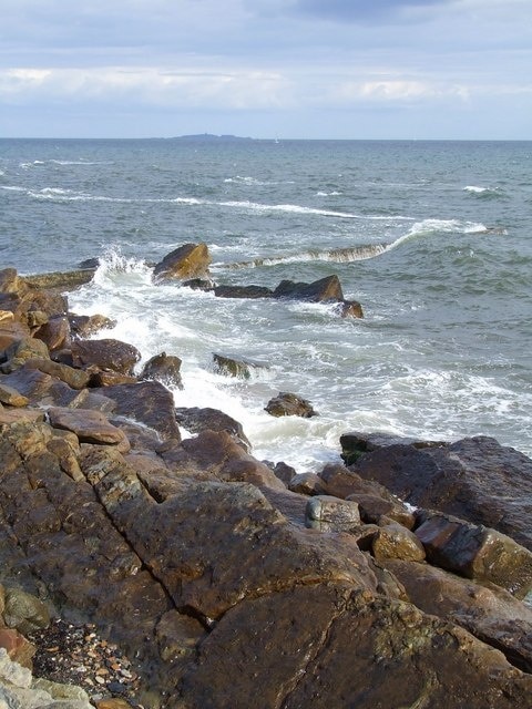 Waves breaking on the old swimming pool The outline of the old swimming pool is visible beyond the rocks of the St Monans coast.