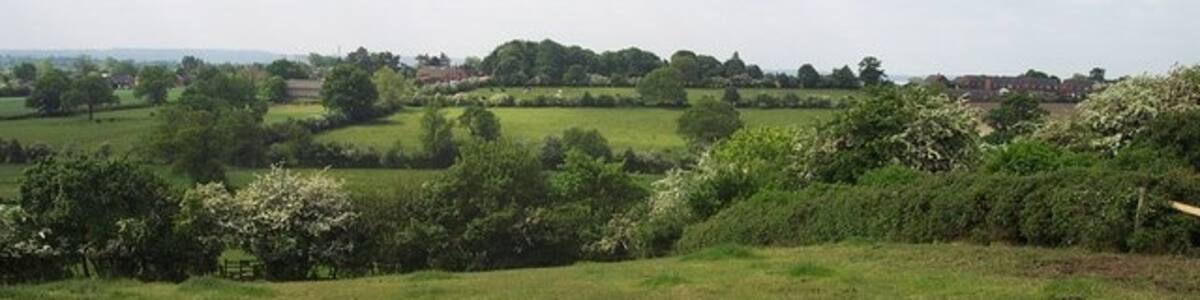 Photo "Footpath above Abbots Bromley. The edge of the village can be seen in the distance" by Geoff Pick (Creative Commons Attribution-Share Alike 2.0) / Cropped from original
