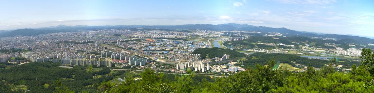 Photo "Cityscape of the metropolitan city of Daejeon, South Korea. This is a panorama of three photograhs stitched together using Hugin. The photographs were taken from Bonghwangjeong at Gyejoksan, a nearby mountain, using a 20mm focal length (crop factor 1.5) with aperture f/11." by YooChung (Creative Commons Attribution-Share Alike 3.0) / Cropped from original