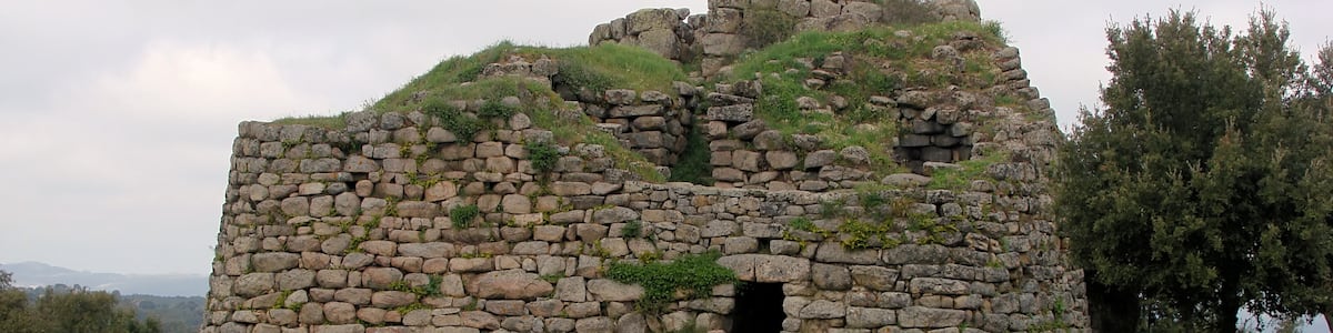 Photo "Nuraghe Loelle (1200–900 BC) along the SS389 near Buddusō, Sardinia, Italy" by Biopics (Creative Commons Attribution-Share Alike 3.0) / Cropped from original