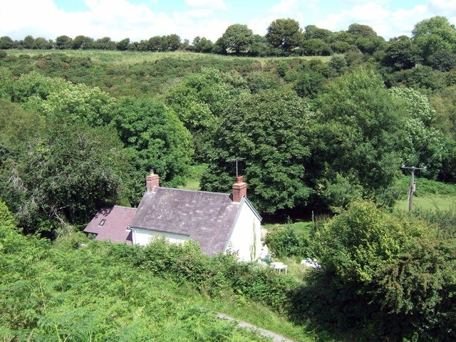 Leafy valley of Afon Brynberian The valley here is little more than a cleft between steep sides and the lane zigzags up the slope above this little house tucked away close by the ford. Further to the right of the image there are rocky crags.