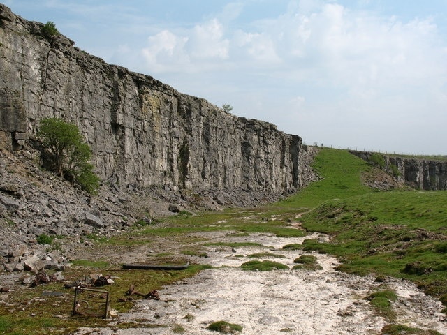 Preston Quarry If following the public footpath from the tank road towards Preston village, walkers are advised not to try to stick to the official line of the path, unless equipped with a parachute. The sensible way is to use the grassy ramp seen here, then to find a route across the quarry floor. This shot shows the carboniferous limestone face on the left and the bedding plane that one walks across. Preston quarry closed in the 1970's.