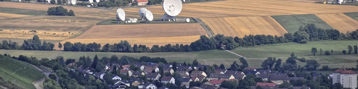 Photo "Bilder vom Flug Nordholz-Hammelburg 2015: Im Vordergrund der Ortsrand von Hammelburg. Dahinter die Antennen von Intelsat-Kommunikations ("Erdfunkstelle Fuchsstadt")." by Ra Boe / Wikipedia (Creative Commons Attribution-Share Alike 3.0 de) / Cropped from original