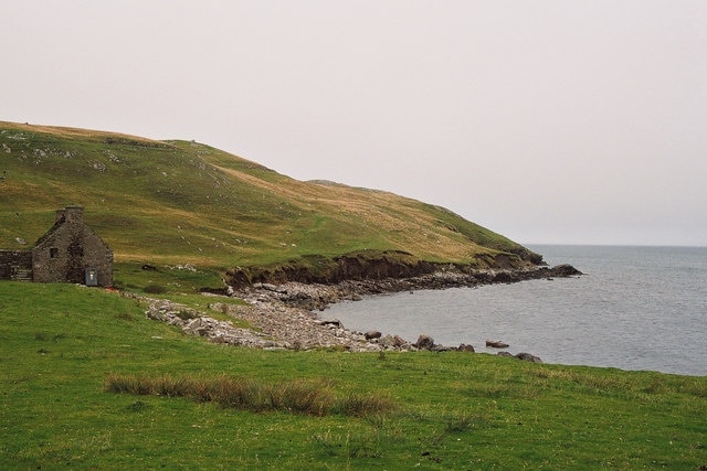 Beach of East Lunna Voe The photo is taken south of Lunna Kirk. The building appears to be deserted - perhaps an old farm? Erosion of the hillside behind the beach is evident from the exposed face with minor slips.