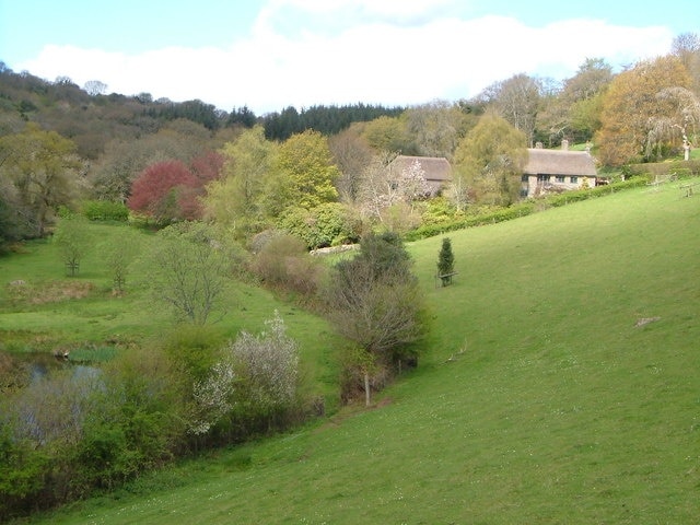 Higher Combe, Lustleigh. Thatched farmhouse and outbuildings on the side of a pretty valley above Lustleigh. Pond lower left.