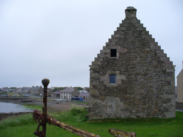 The Old Granary, St Mary's, Orkney: an old red sandstone building with stepped gable between the main road through the village and the shore