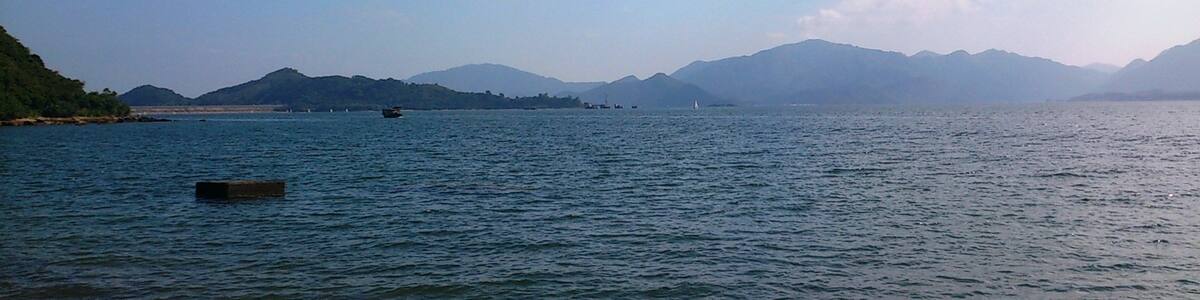 Photo "Plover Cove Reservoir Dam and Three Fathoms Cove" by Ceeseven (Creative Commons Attribution-Share Alike 4.0) / Cropped from original