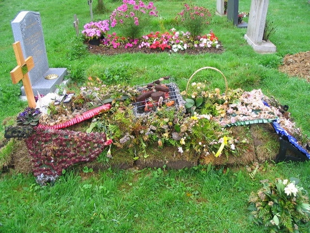 A floral tribute with a centrepiece of sausages, beefburger and kebab marking a recent grave in the churchyard at Thorpe-le-Soken.