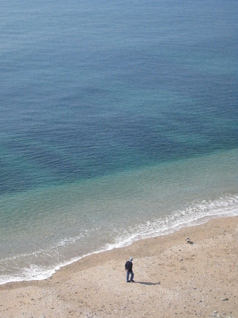 One man and his dog The beach below Mounts Road Porthleven.