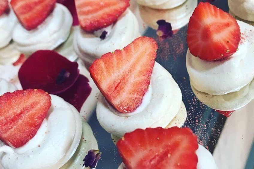 Mini meringues with a cheesecake filling , strawberries and rose petals