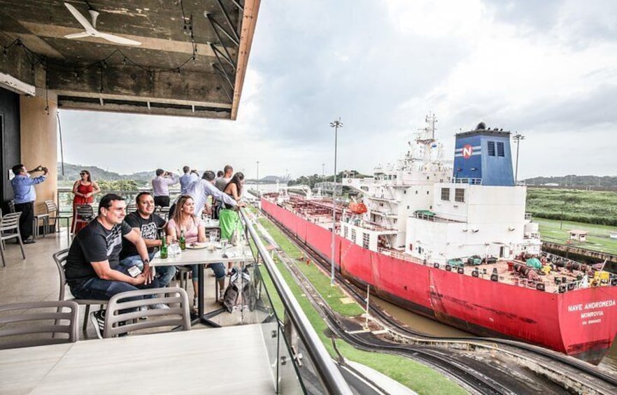 Onlookers watch as a ship cruises down the narrow Panama Canal.