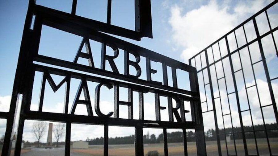 Enter the prison camp, passing the infamous "Arbeit Macht Frei"