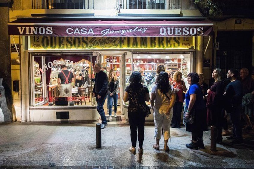 Guide prepares a group to visit a cozy tapas bar and taste specialties like salted cod and Iberian ham.
