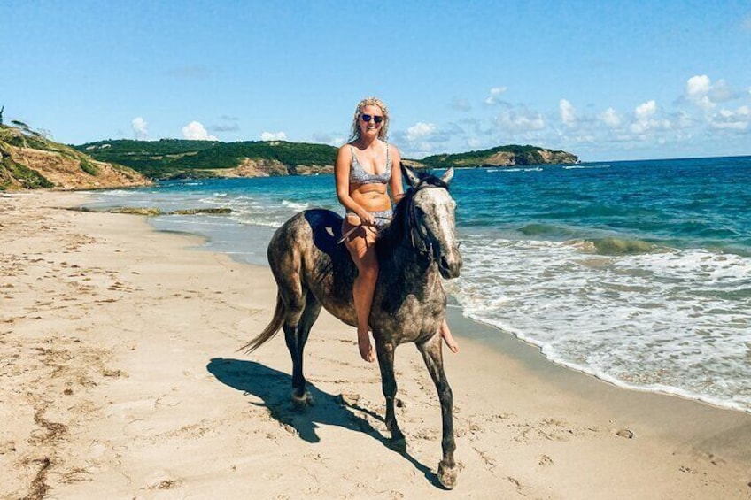 Lady horseback riding along the beach.