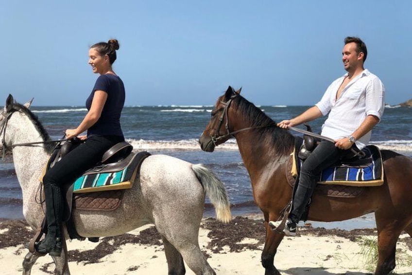 A couple riding along the beach.