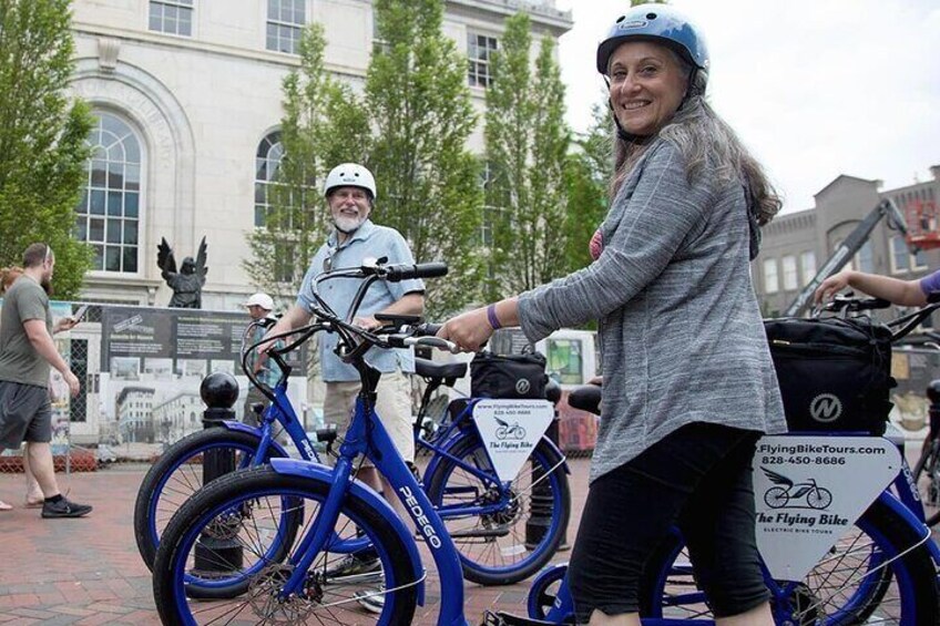 Group walking e-bikes in downtown Asheville