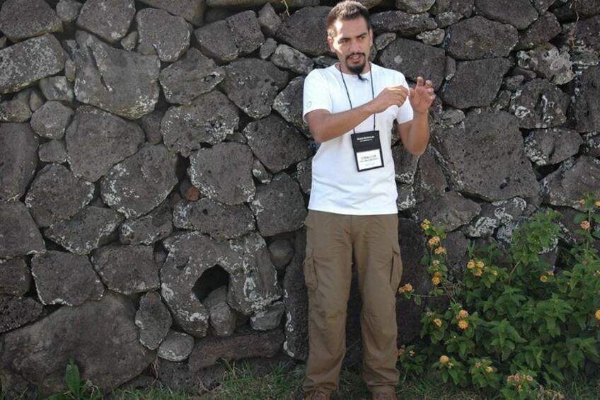 Rapanui historian Cristián Moreno Pakarati talking next to a Hare Moa structure for a Road Scholar group in Tahai Archaeological Complex. Starting point of the Moai Rise and Fall Field Trip.