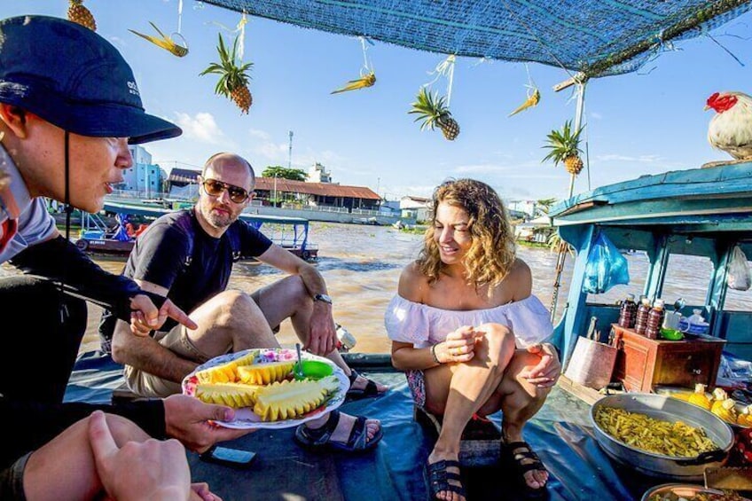 Visitors try local fruits at floating market