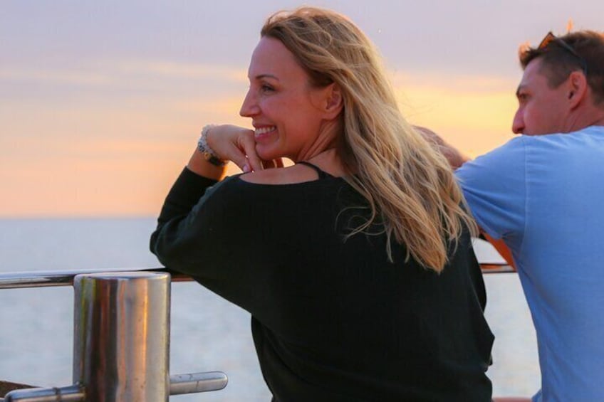 Couple watching the sunset on the bow of the boat