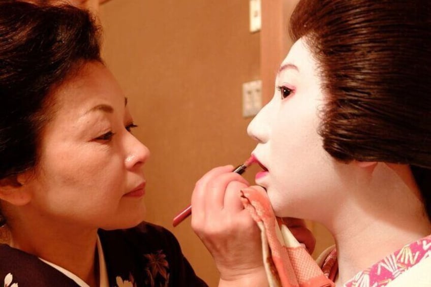 Senior geisha helping a young geisha with her makeup