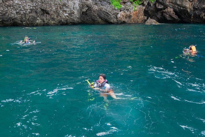 Snorkelers surface in the tropical waters of Phi Phi island on this speedboat adventure trip.