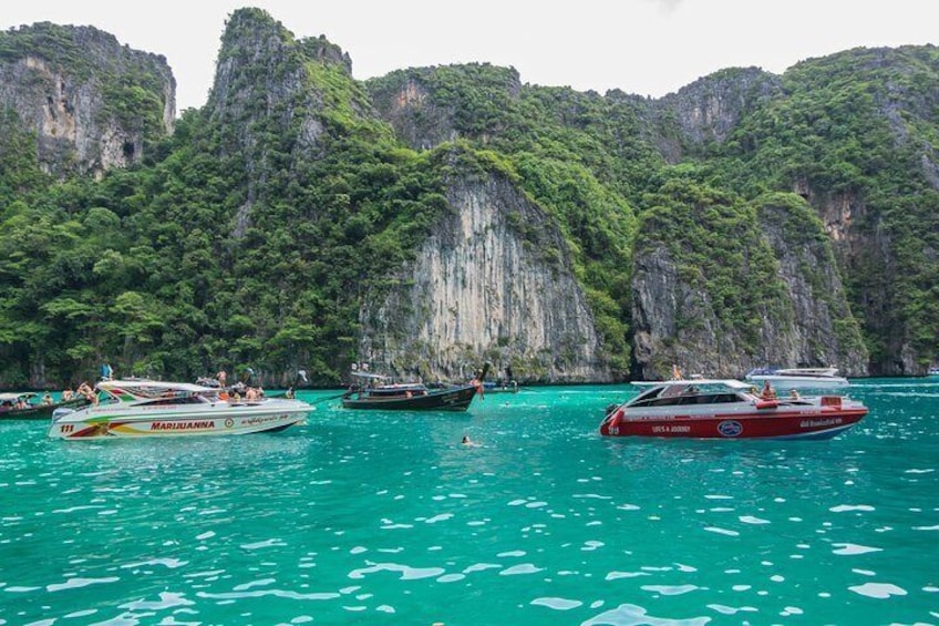 Speedboats gather around Phi Phi Island for travelers to snorkel in the clear blue waters.