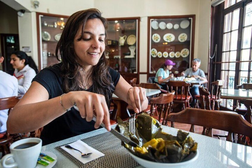 Tour guide introduces travelers to tamale, a traditional South American dish typically made of corn-based dough which is steamed in a banana leaf.