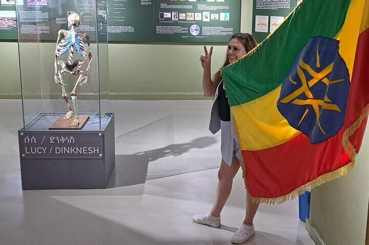 Visitor holding the national flag of Ethiopia standing next to Lucy at the National Museum of Ethiopia in Addis Ababa