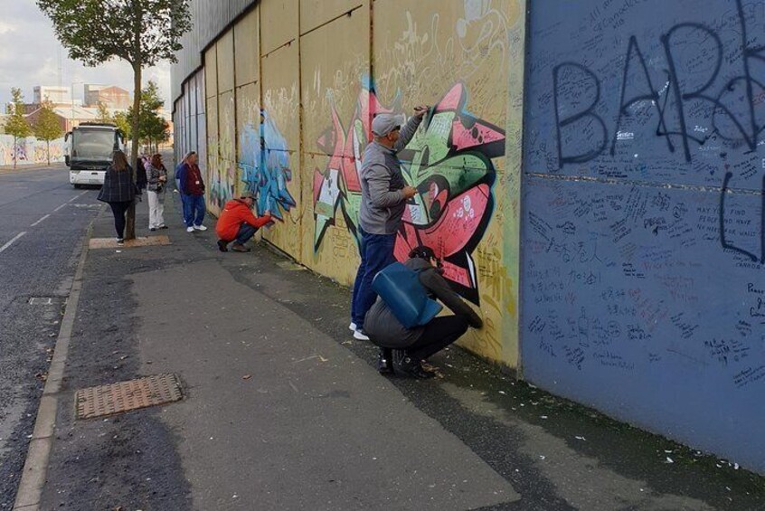 visitors leaving a message of peace on Belfast's first peace wall