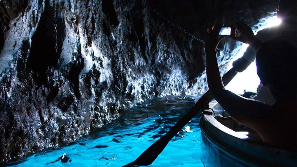 Tourists boating through The Blue Grotto sea cave on the coast of Capri in southern Italy