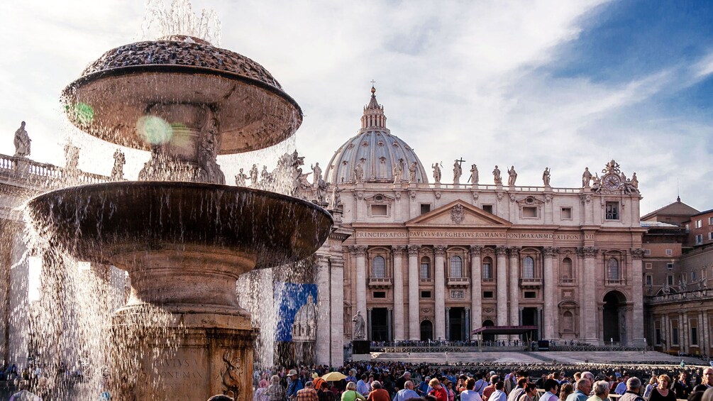 Closeup of a water fountain with Saint Peter's Basillica in the background.