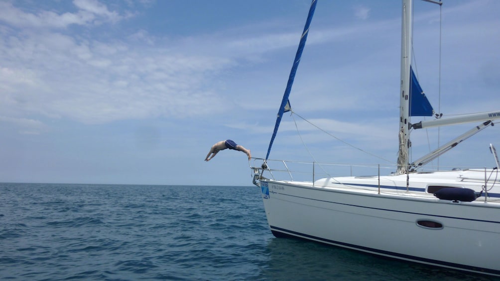 man diving off bow of sailboat on Mediterranean in Barcelona