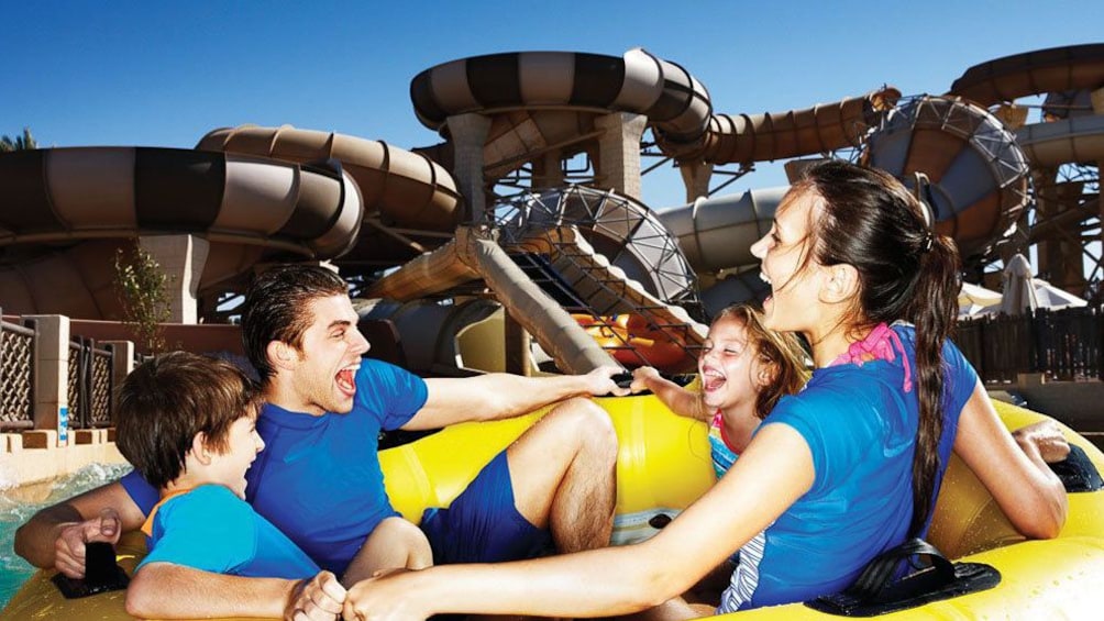 group of four going down water slide in an inner tube at water park in Dubai