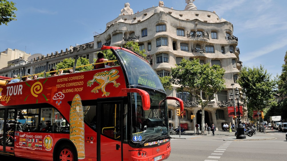 passengers on open air tour bus driving by Casa Batlló in Barcelona