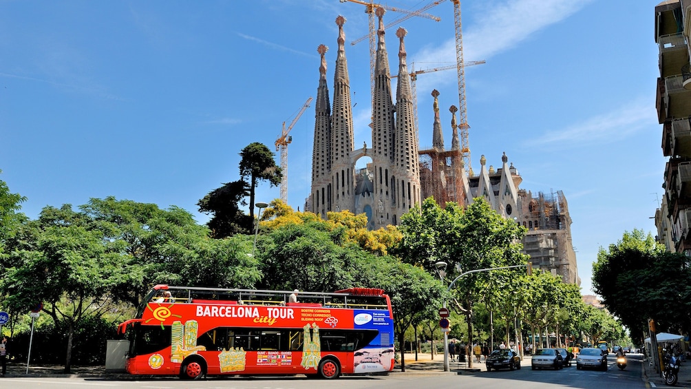 passengers on open air tour bus driving by Sagrada Família church in Barcelona