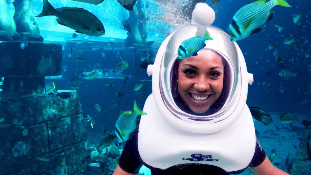 woman in scuba helmet swimming inside aquarium in Dubai