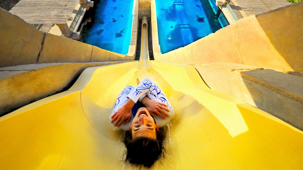 woman sliding down very steep water slide at water park in Dubai