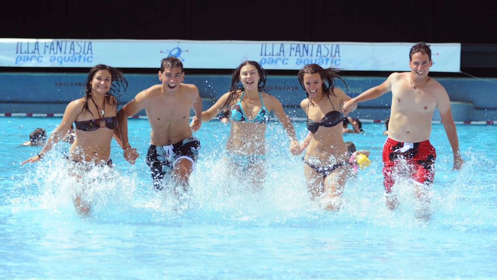 three girls and two guys running through water at water park in Barcelona