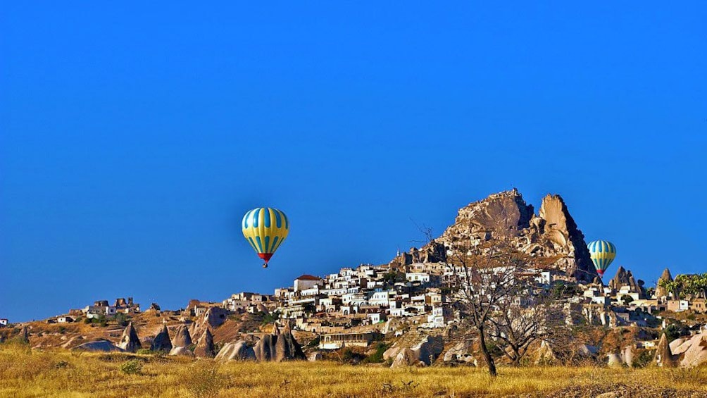 Hot air balloons float in the blue skies above Cappadocia  