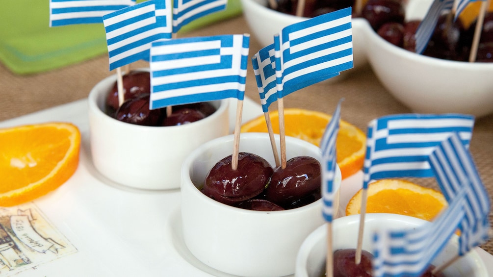 Small bowls of olives speared with miniature Greek flags