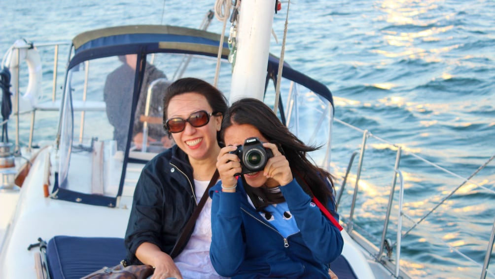 Two women taking photos on deck of sailboat in San Diego