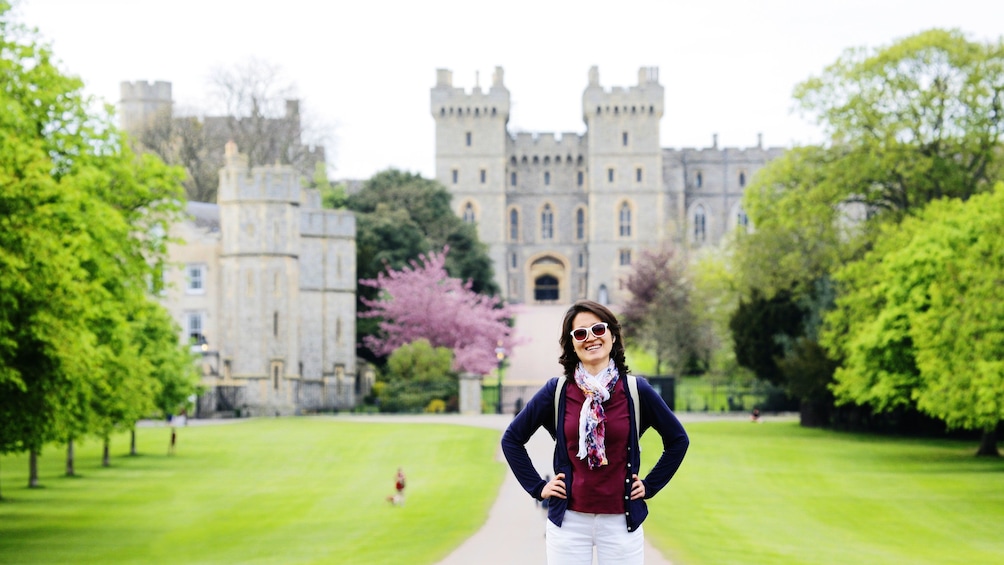 happy woman poses in front of Buckingham Palace in London