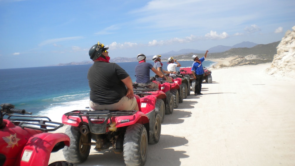 people driving many ATV's riding along shoreline in Los Cabos