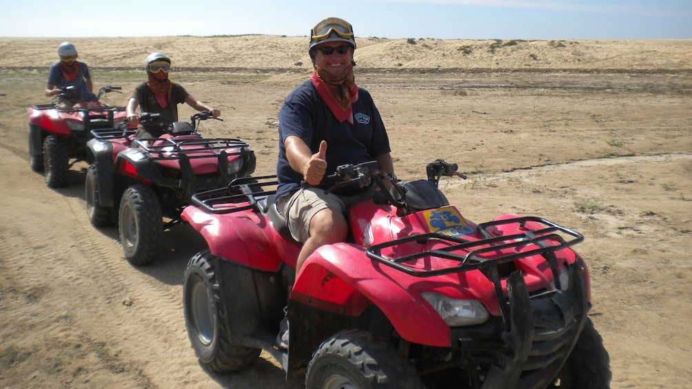 three people riding at ATV's on the beach in Los Cabos