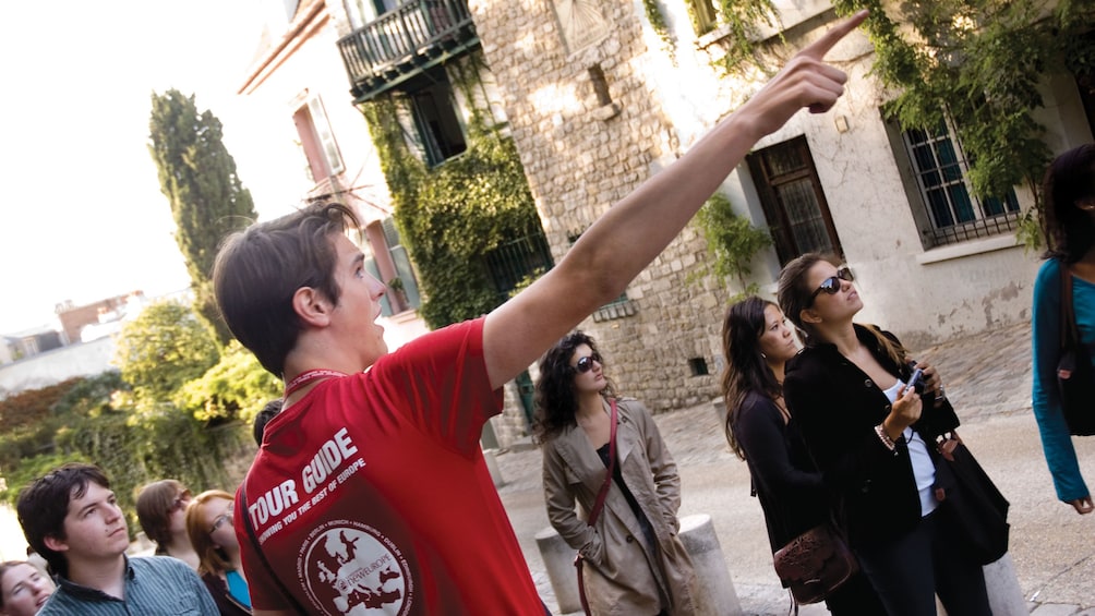 Show item 1 of 6. Tour guide pointing to a building in Paris.