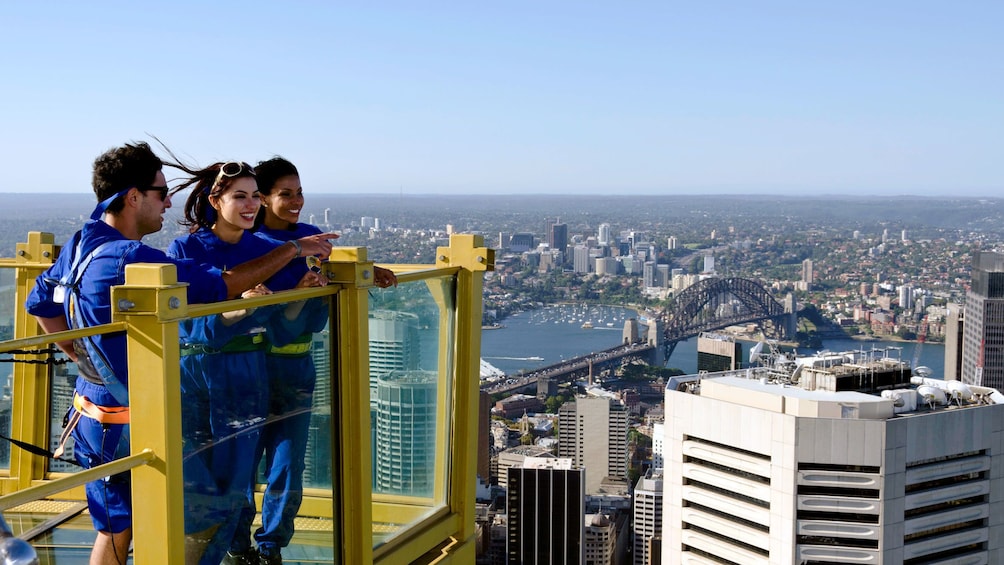 Guests on the Skywalk at the Sydney Tower Eye take a break standing on a platform overlooking the city in Sydney